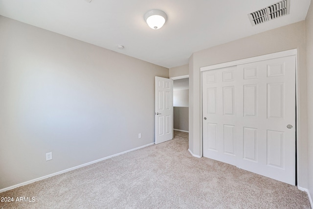 unfurnished bedroom with a closet and light carpet