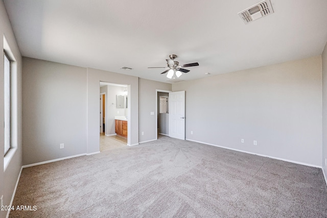 unfurnished bedroom with ceiling fan, connected bathroom, and light carpet