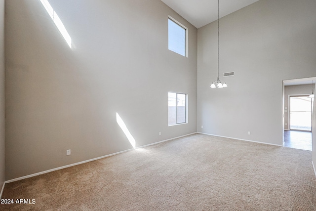 empty room featuring high vaulted ceiling, an inviting chandelier, and carpet