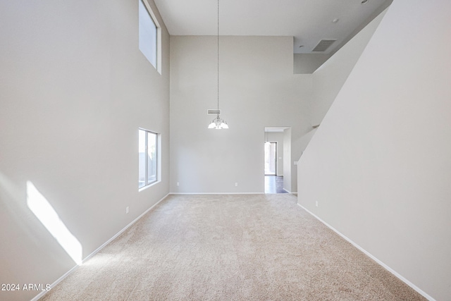 spare room with a high ceiling and light colored carpet