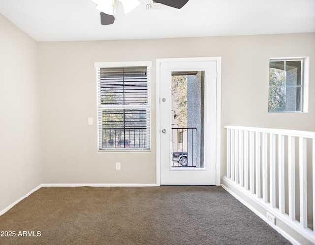 doorway featuring ceiling fan and carpet