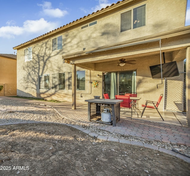 rear view of property featuring ceiling fan and a patio area