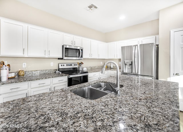 kitchen with sink, white cabinetry, stainless steel appliances, and dark stone counters