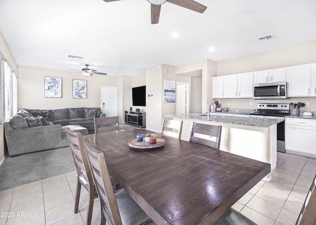 tiled dining area with ceiling fan and sink