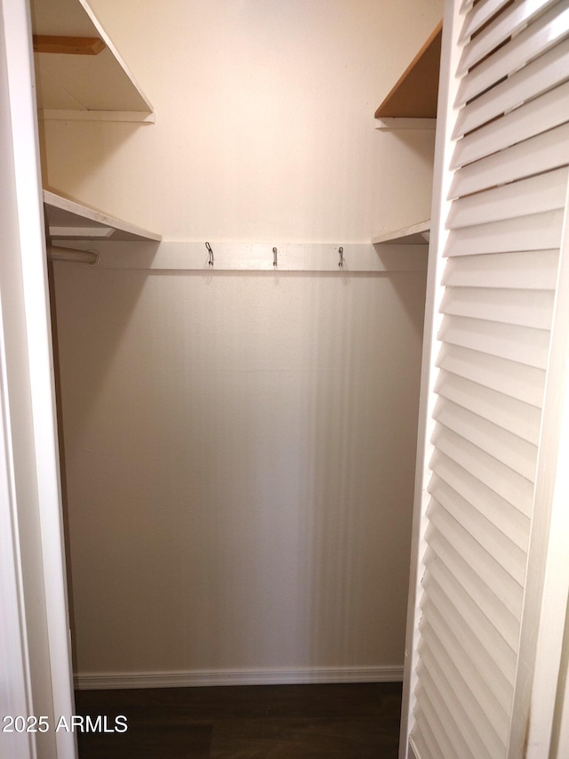 walk in closet with dark wood-type flooring