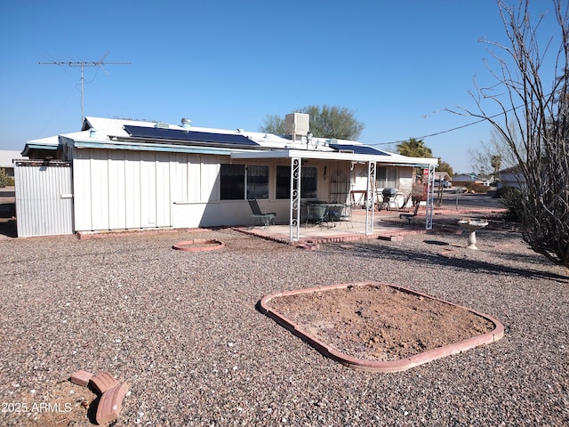 back of property with a patio area and solar panels