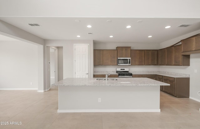 17633 W Palo Verde Dr, Litchfield Park, AZ 85340 - kitchen with stainless steel appliances, recessed lighting, light stone counters, a center island with sink, and light tile patterned flooring