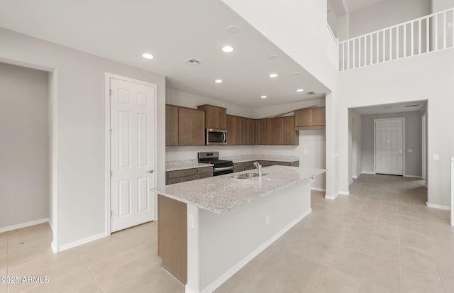 17633 W Palo Verde Dr, Litchfield Park, AZ 85340 - kitchen with stainless steel appliances, recessed lighting, a kitchen island with sink, light tile patterned floors, and light stone counters