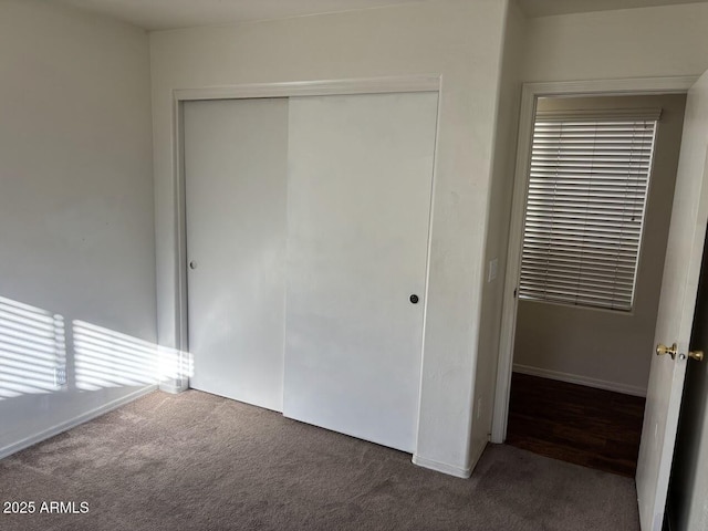 unfurnished bedroom with dark colored carpet and a closet