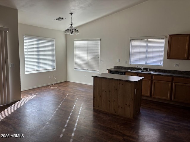 kitchen with a sink, vaulted ceiling, a center island, dark countertops, and decorative light fixtures