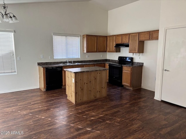 kitchen featuring under cabinet range hood, a center island, black appliances, dark countertops, and pendant lighting