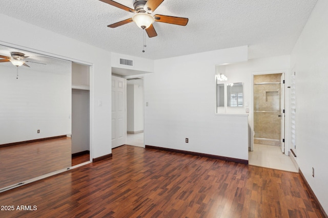 unfurnished bedroom with a textured ceiling, ceiling fan, dark hardwood / wood-style floors, and connected bathroom