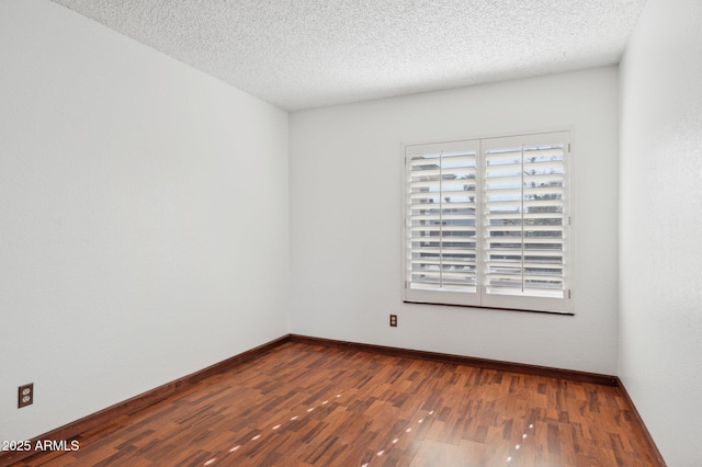 spare room with a textured ceiling and dark hardwood / wood-style flooring