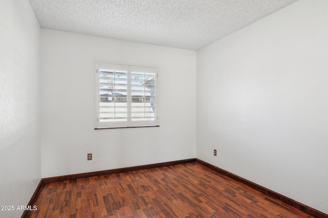 spare room with a textured ceiling and dark hardwood / wood-style flooring