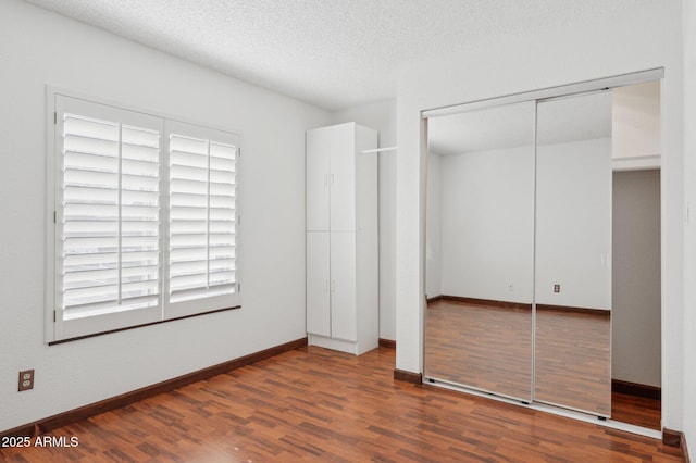 unfurnished bedroom featuring a textured ceiling, a closet, and hardwood / wood-style flooring