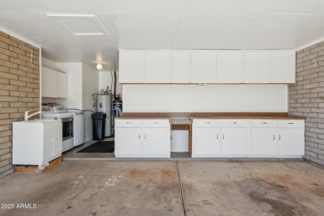 kitchen featuring washer / dryer, water heater, white cabinets, and brick wall