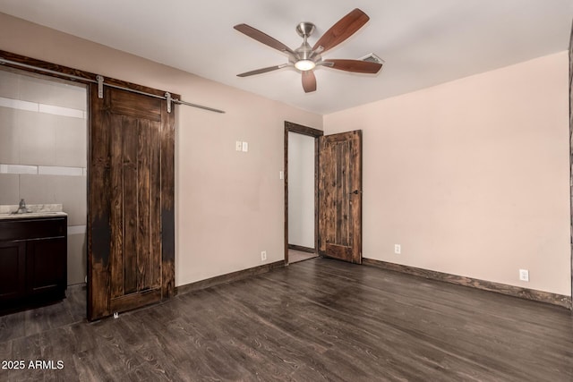8542 N 30th Dr, Phoenix, AZ 85051 - unfurnished bedroom with dark wood finished floors, a barn door, baseboards, a sink, and a ceiling fan
