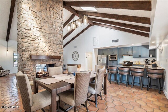 tiled dining room with a fireplace, beam ceiling, and high vaulted ceiling