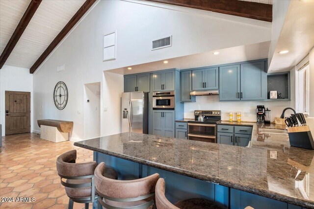 kitchen with appliances with stainless steel finishes, beam ceiling, high vaulted ceiling, and dark stone countertops