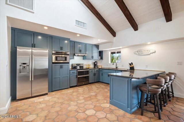 kitchen featuring kitchen peninsula, sink, a breakfast bar area, beamed ceiling, and stainless steel appliances