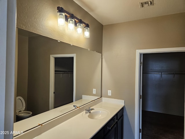 full bath featuring visible vents, toilet, a spacious closet, and vanity