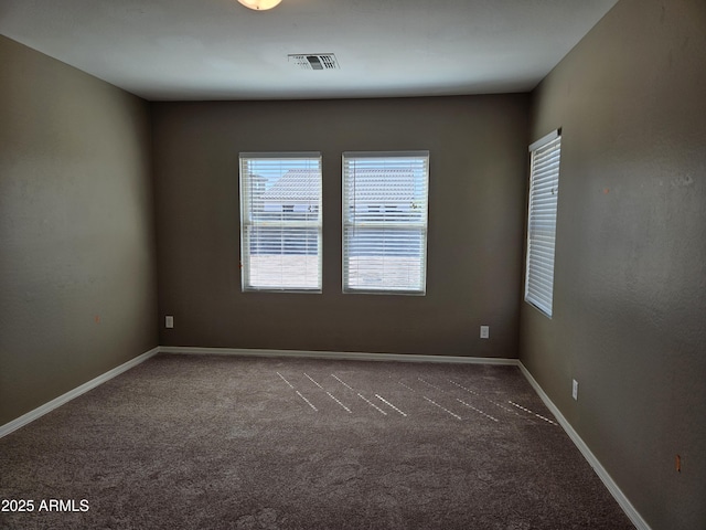 empty room with carpet, visible vents, and baseboards