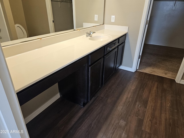 bathroom featuring a spacious closet, vanity, baseboards, and wood finished floors