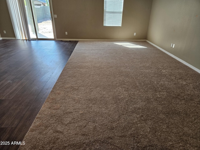 spare room featuring dark wood-style floors and baseboards