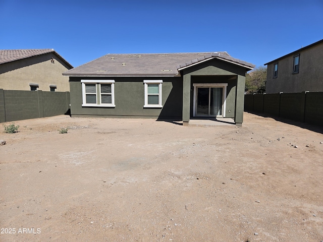 rear view of property with stucco siding, a fenced backyard, and a tile roof