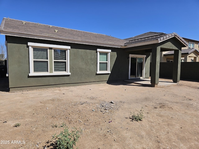 rear view of property with a shingled roof, a patio area, and stucco siding