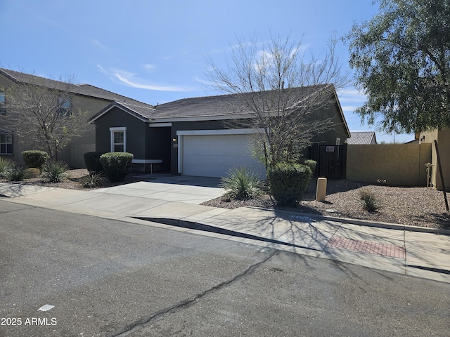 view of front of property featuring stucco siding, driveway, a garage, and fence