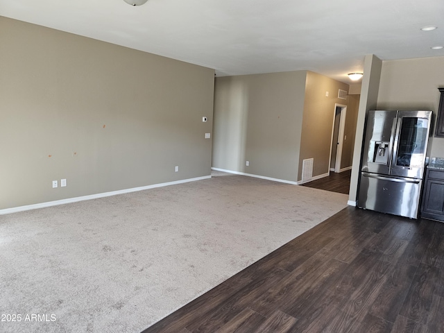 unfurnished living room featuring visible vents, dark carpet, baseboards, and dark wood-style flooring