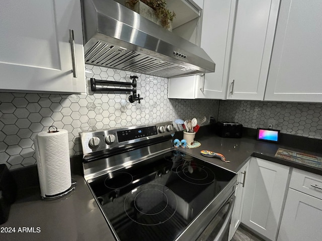 kitchen with electric range, backsplash, and wall chimney range hood