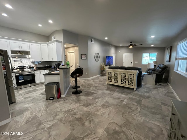 kitchen featuring tasteful backsplash, ceiling fan, stainless steel range oven, white cabinets, and a breakfast bar area