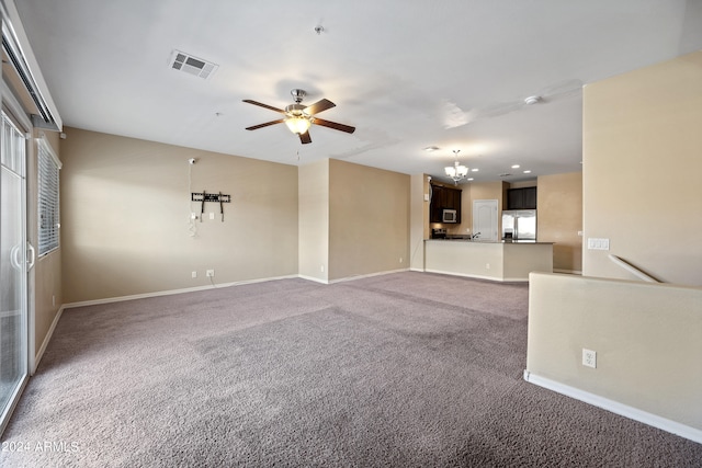 unfurnished living room featuring ceiling fan with notable chandelier and carpet flooring