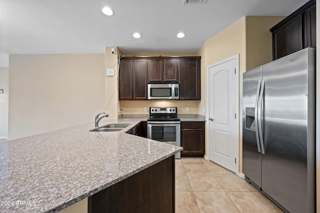 kitchen with light stone counters, light tile patterned floors, sink, dark brown cabinets, and stainless steel appliances