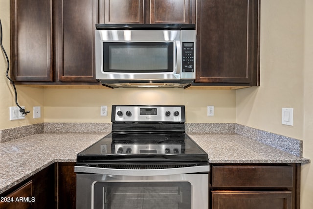 kitchen with dark brown cabinets, light stone countertops, and appliances with stainless steel finishes