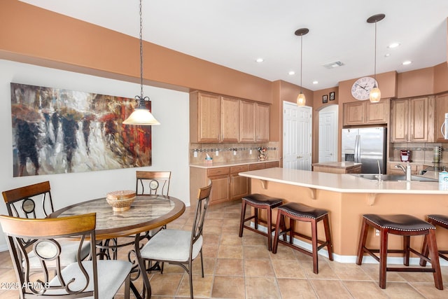 kitchen with sink, hanging light fixtures, appliances with stainless steel finishes, and tasteful backsplash