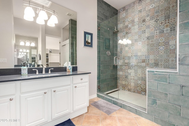 bathroom featuring a shower with door, an inviting chandelier, tile patterned floors, and vanity