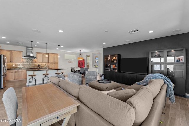 living area featuring light wood finished floors, visible vents, and recessed lighting