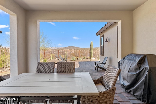 view of patio / terrace featuring fence, a mountain view, and outdoor dining area