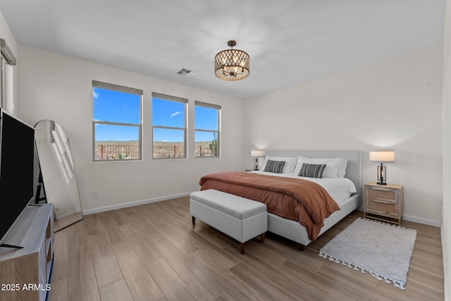 bedroom with light wood finished floors, baseboards, and visible vents