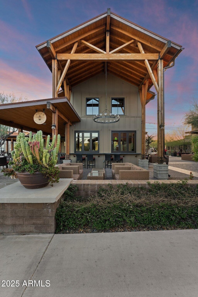 view of exterior entry with board and batten siding, a patio area, and an outdoor living space