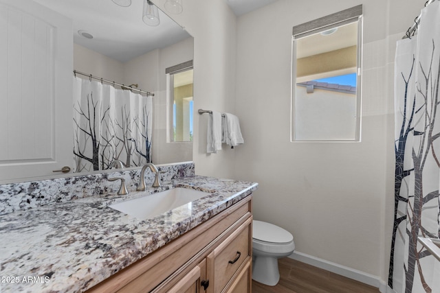 bathroom with vanity, wood finished floors, toilet, and baseboards