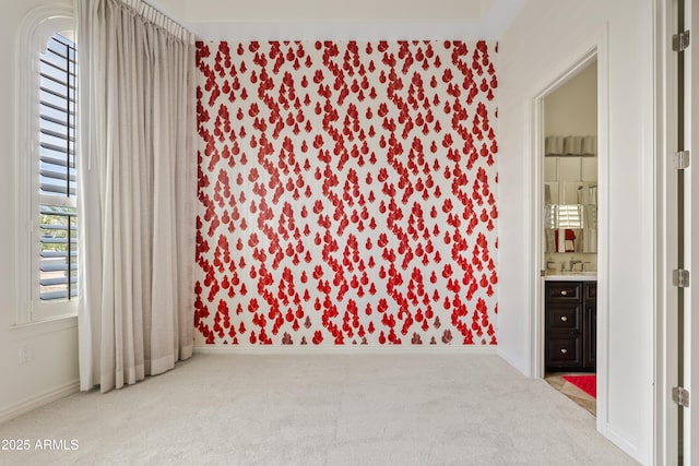 unfurnished room featuring a sink, carpet floors, and baseboards