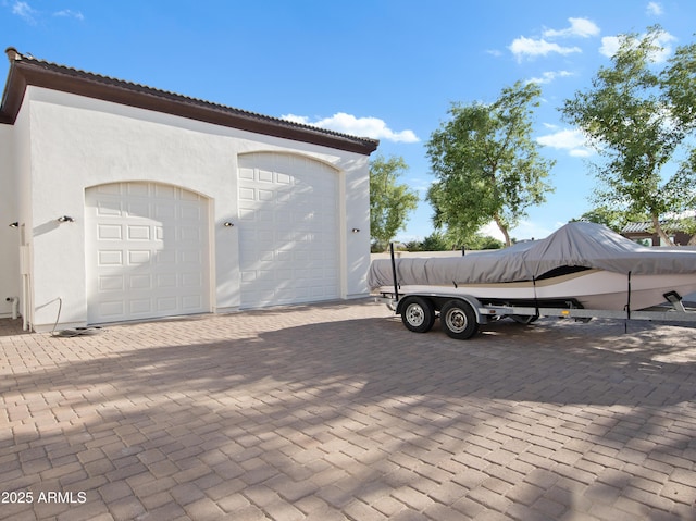 exterior space with a tiled roof, a garage, stucco siding, and an outbuilding