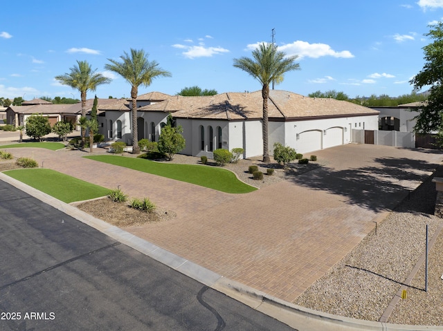 ranch-style house featuring an attached garage, stucco siding, fence, and decorative driveway