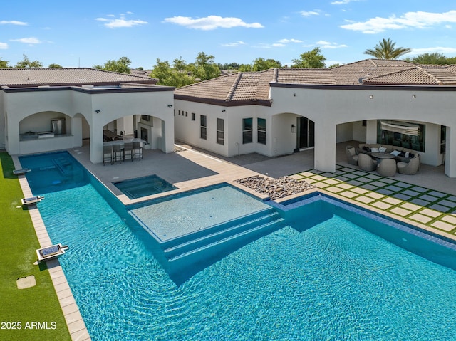 rear view of property featuring a pool with connected hot tub, outdoor wet bar, stucco siding, a patio area, and a tile roof