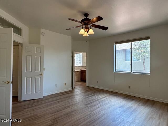 unfurnished bedroom with connected bathroom, ceiling fan, and hardwood / wood-style floors