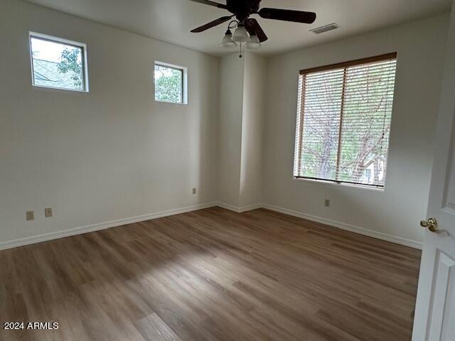 spare room featuring ceiling fan, hardwood / wood-style flooring, and plenty of natural light